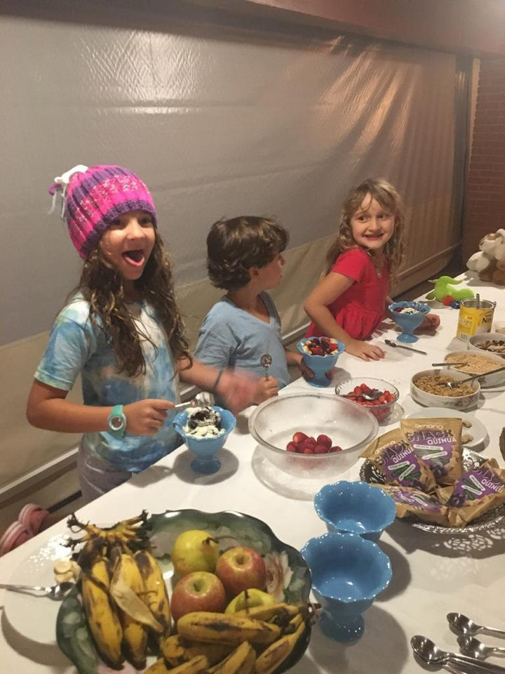 As crianças da família na mesa de uma festa, com frutas e snacks Amana